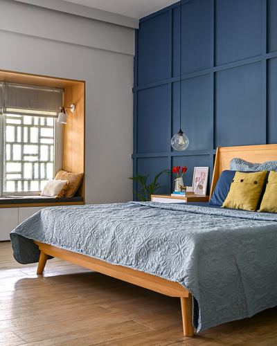 Bedroom with blue paneled wall, wooden bed, and window seat nook with cushions