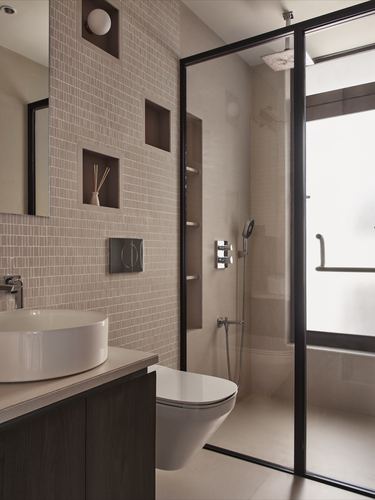 Beige tiled bathroom with niches, vessel sink, wall-hung toilet, and glass-enclosed shower