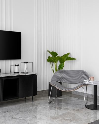 Living room corner with houndstooth chair, marble table, plant and black fluted TV console