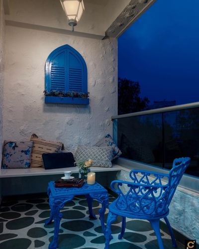 Blue-lit balcony seating nook with faux arched window and cast-iron chair at dusk