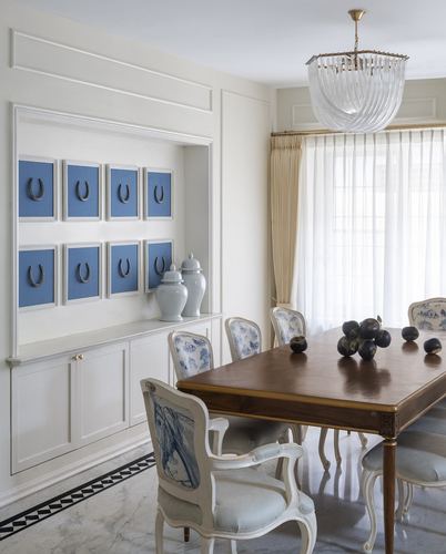 English-country style dining room with wood table, cane chairs, blue-framed horseshoe art, and marble floor