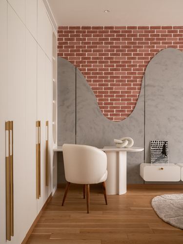 Study nook with wave-shaped stone panel, brick wall, curved desk and cream chair