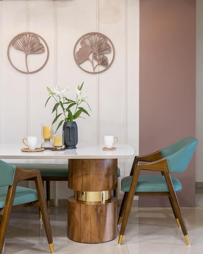 Dining table with marble top on wooden pedestal base, teal chairs, ginkgo wall art behind