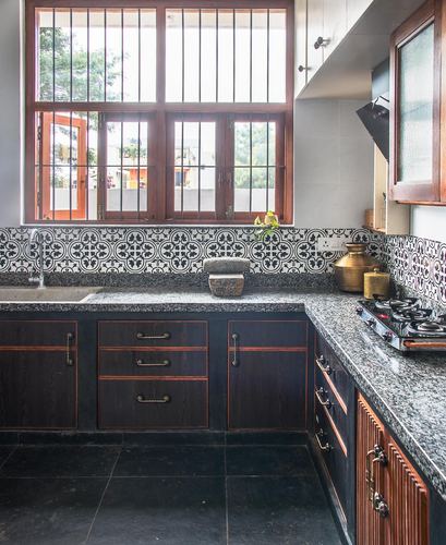 L-shaped kitchen with dark wood cabinets, granite counters, patterned tile backsplash, and large barred window
