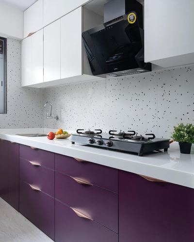 Modern kitchen with purple lower cabinets, white countertop, terrazzo backsplash, black chimney hood