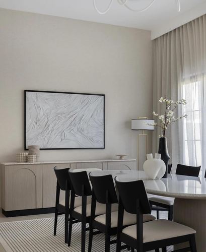Dining area with beige sideboard, black chairs, stone table and abstract art on wall
