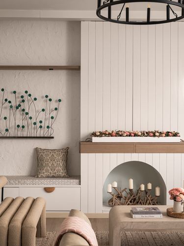 Living room with fluted white paneling, arched niche with candles, textured wall art, and beige seating