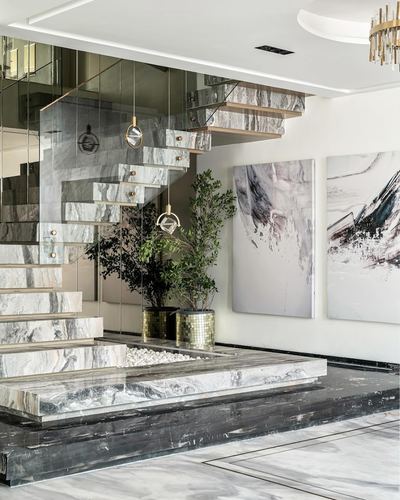 Floating marble staircase with glass railing beside abstract art and potted plants