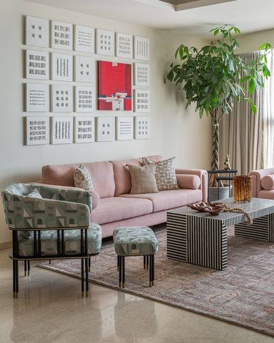Living room with pink sofa, patterned armchair, striped coffee table and gallery wall of white artworks with red accent piece