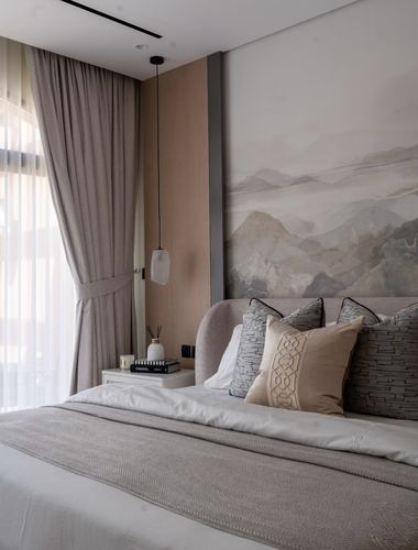 Neutral-toned bedroom with curved upholstered headboard, layered pillows, and large mountain wall art