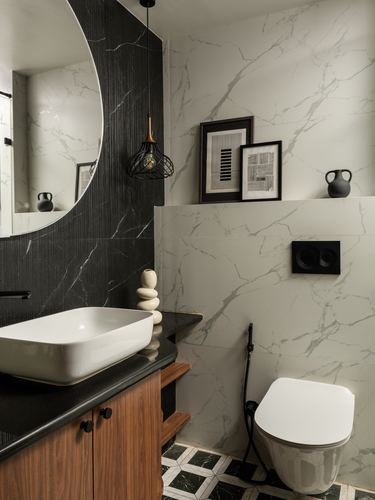 Bathroom with round mirror, black textured stone wall, marble tile, wood vanity and wall-hung toilet