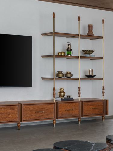Wooden TV console with brass-poled open shelving displaying brass vessels and lanterns