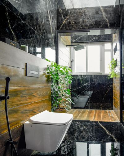 Dark veined stone bathroom with wood-look wall, wall-hung toilet, glass shower and plants