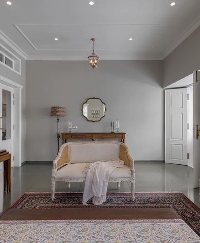 Foyer with cane settee, console table, round mirror and pendant light on grey walls