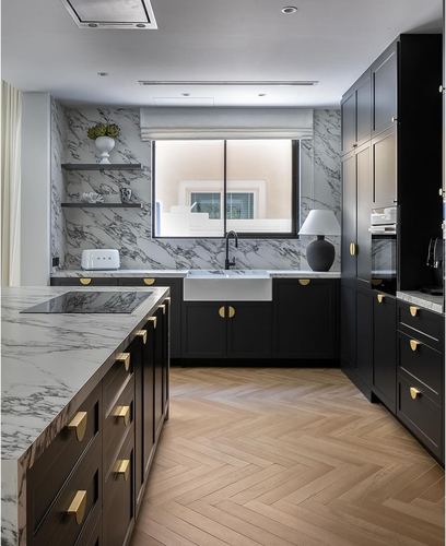 black and white marble kitchen with brass hardware and herringbone wood floor