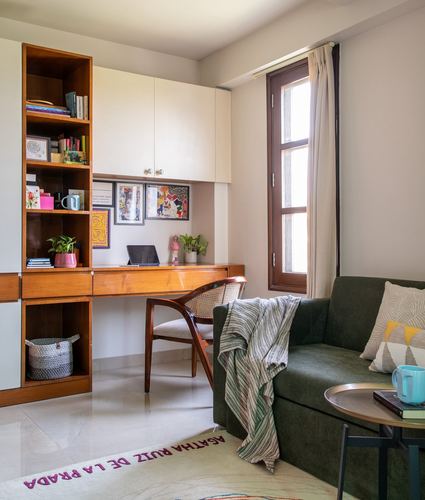 Study nook with wood desk, cane chair, bookshelf, and green sofa in daylight
