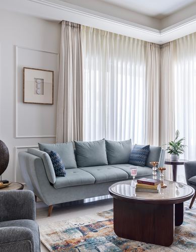 Sage sofa with patterned cushions faces round marble-top coffee table in soft-lit living room