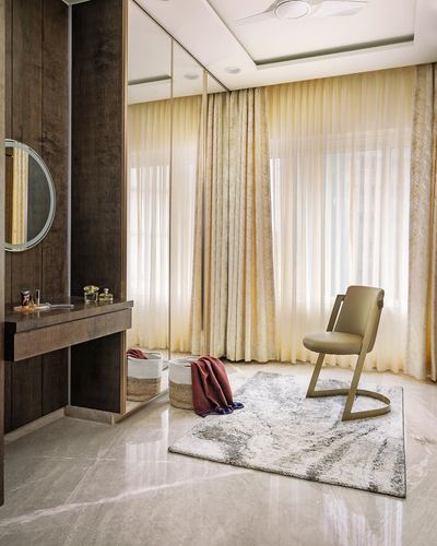 Sunlit dressing corner with round mirror, dark wood console, sheer curtains and cane chair on rug
