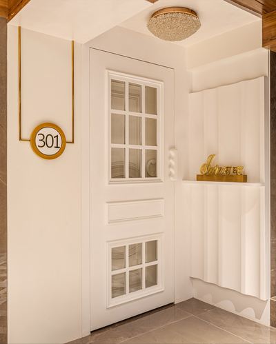 White paneled entry door with glass panes beside a fluted niche and gold 301 plaque