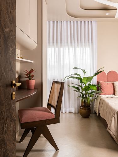 Bedroom corner with cane chair, study nook, sheer curtains and scalloped pink headboard