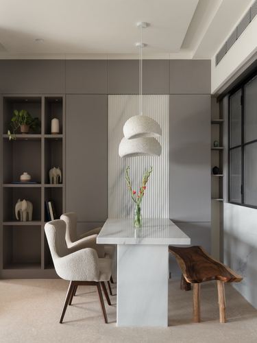 Dining nook with fluted marble table, boucle armchairs, live-edge bench and layered pendant light