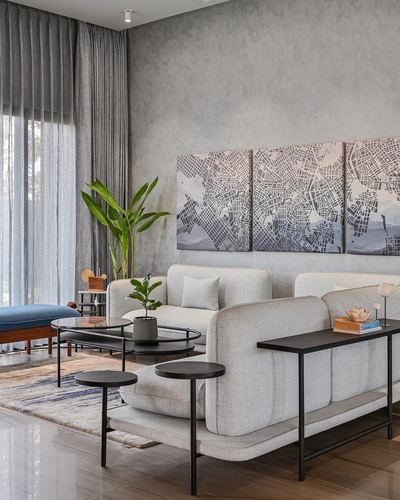 Neutral living room with textured grey wall, map triptych art, and light upholstered sofa with black metal tables