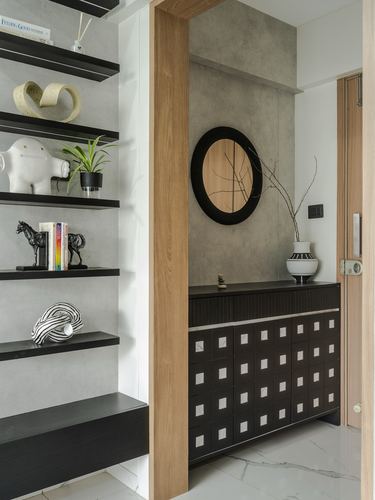 Entryway with wooden archway, round mirror, black perforated console, and open display shelving.