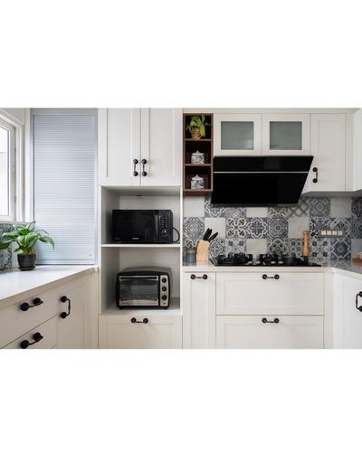 White shaker kitchen corner with patterned blue tile backsplash, black chimney hood, and built-in microwave niche.