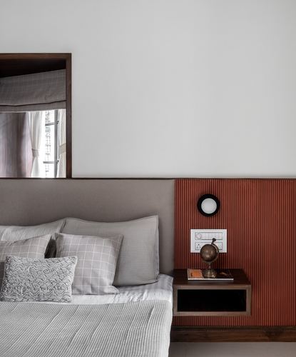 Bedroom corner with grey upholstered headboard, fluted terracotta panel, and floating wood nightstand