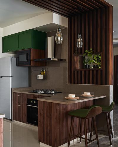 Open kitchen with green cabinets, walnut counter, and wooden louvered partition with plant niche