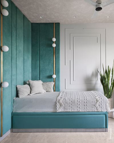 Bedroom with tall teal velvet channel headboard wall, brass trim globe lights, and white knit bedding