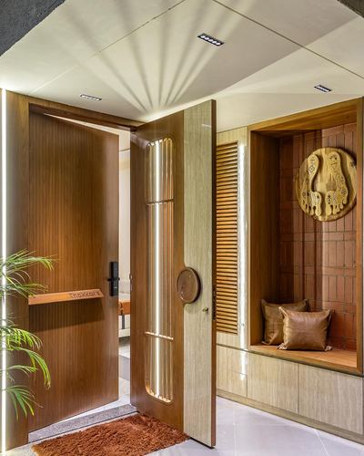Entryway with wooden pivot door, backlit fluting, and terracotta niche seating nook