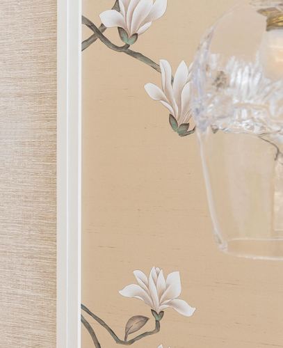 Close-up of magnolia wallpaper beside grasscloth panel and a crystal pendant lamp shade