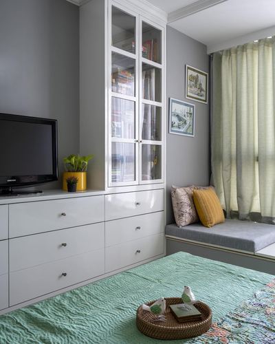 Bedroom corner with white cabinetry, glass bookcase, window seat and mint green bedspread
