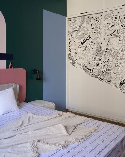 Bedroom with pink headboard, teal wall, and wardrobe covered in black-and-white graphic decal art