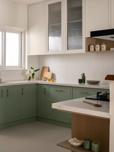 L-shaped kitchen with sage green lower cabinets, white upper units, and tiled backsplash