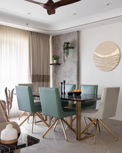 Dining room with sage green leather chairs around a marble table with brass legs