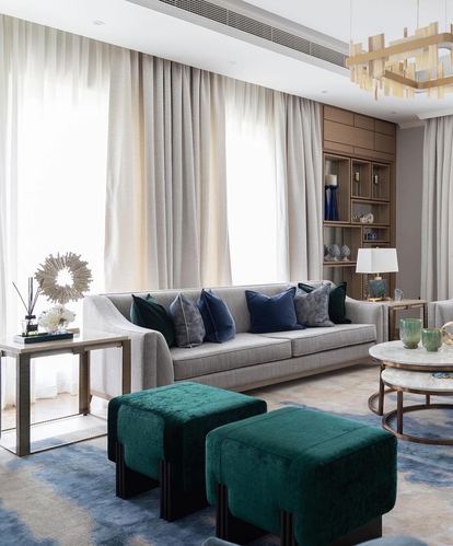 Living room with grey sofa, teal velvet ottomans, sheer curtains and gold chandelier