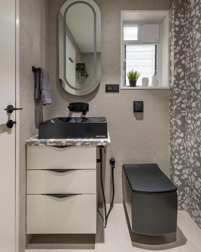 Small modern bathroom with black basin, oval mirror, terrazzo wall, and wall-hung toilet
