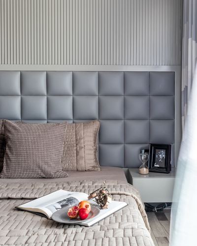 Grey quilted headboard bedroom with taupe linens and styled bedside tray of pomegranates