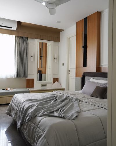 Neutral bedroom with panelled wardrobe, mirror, window bench and grey upholstered bed