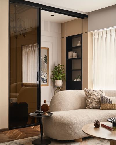 Curved cream boucle sofa beside black-framed glass sliding door and open black shelving unit