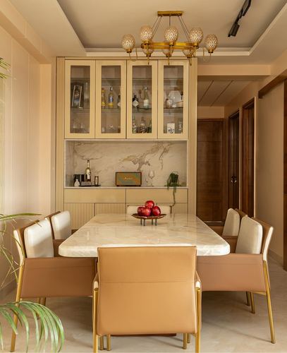 Beige dining room with marble table, glass-front bar cabinet and amber chandelier
