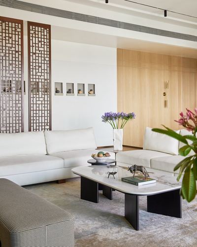 Living room with white sectional sofa, marble coffee table, wooden fretwork screens and wall niches