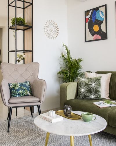 Living room corner with olive green sofa, blush tufted armchair, marble coffee table, and framed art