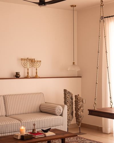 Living room corner with striped sofa, carved wood panels, brass candelabra, and a hanging wooden swing