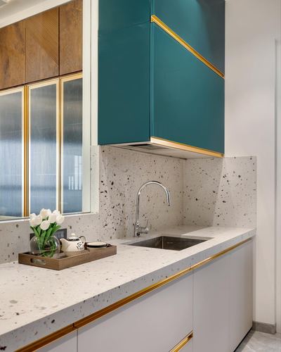 Kitchen corner with teal gloss cabinet, terrazzo counter, brass-edged sink and tulip bouquet in tray