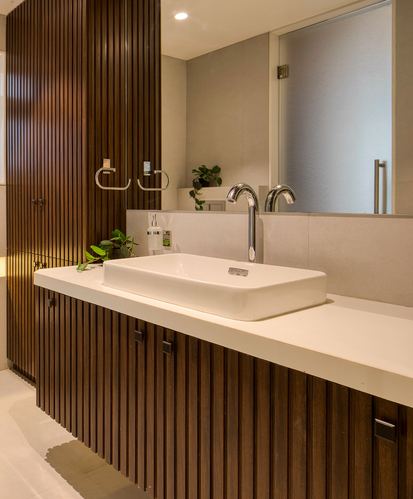 Bathroom vanity with fluted wood cabinetry, white countertop, rectangular vessel sink and mirror
