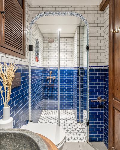 Bathroom with cobalt blue subway tile, arched glass shower, and patterned cement floor