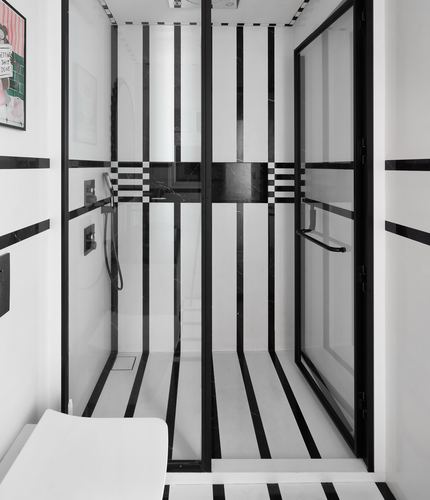 Black and white striped marble bathroom with glass shower enclosure and matching linear pattern